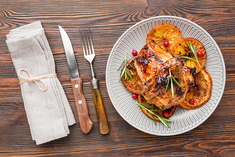 top-view-baked-chicken-orange-slices-plate-with-cutlery-napkin (1)